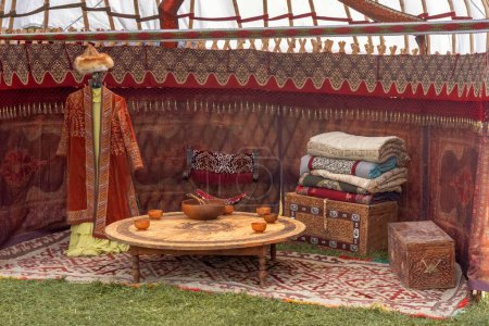Téléchargez les photos : Décoration intérieure d'une yourte nomade traditionnelle : coffre, oreillers et couvertures, tapis de feutre, vêtements nationaux - en image libre de droit