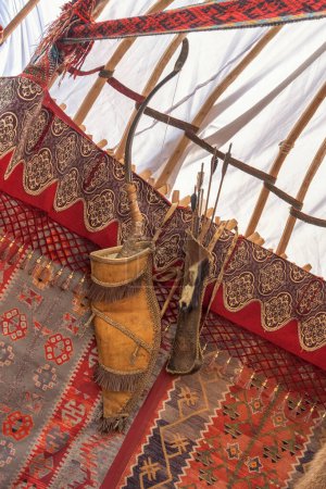 Téléchargez les photos : Arc traditionnel asiatique en bois avec des flèches accrochées au mur de feutre d'une yourte - la maison des nomades - en image libre de droit
