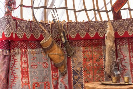 Téléchargez les photos : Arc traditionnel asiatique en bois avec des flèches accrochées au mur de feutre d'une yourte - la maison des nomades - en image libre de droit