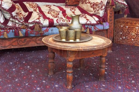 Téléchargez les photos : La cruche et les tasses traditionnelles asiatiques en argent se dressent sur une vieille table en bois dans une yourte - la maison des nomades. - en image libre de droit