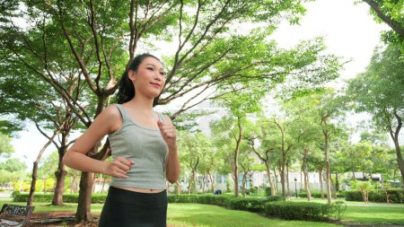 Téléchargez les photos : Jogging femme asiatique en cours d'exécution dans le parc public vert sur belle journée d'été. Sport fitness jogging extérieur pour une subvention saine - en image libre de droit