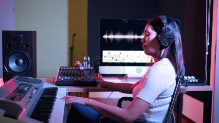 Photo for Beautiful stylish young woman sound producer sitting at the controls in the recording studio - Royalty Free Image