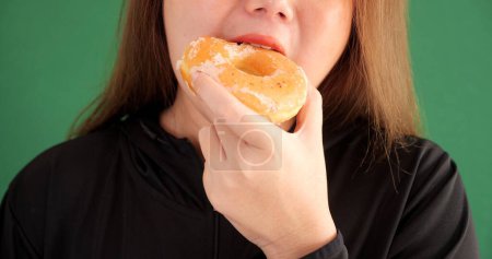 Photo for Close up of woman posing isolated over green background choosing between donuts sweeties - Royalty Free Image