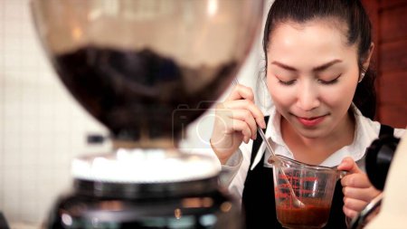 Téléchargez les photos : Heureuse asiatique femme barista faire du café dans le comptoir de café. Barista femme travaillant au Café - en image libre de droit