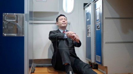 Foto de Asiático hombre vuelo asistente sentado y relajación de trabajar en un avión - Imagen libre de derechos