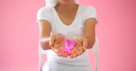 Photo for Hands of woman holding pink ribbon on pink background World breast cancer day concept. Breast cancer symbol - Royalty Free Image
