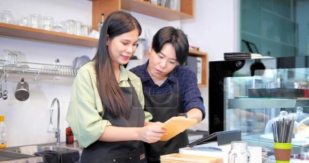 Foto de Dos empleados de barista hablando y discutiendo el trabajo en un restaurante cafetería - Imagen libre de derechos