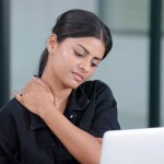 Indian businesswoman sit at workplace experiences severe pain and massaging in neck and exercise. Office syndrome concept