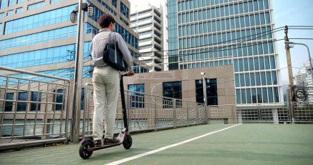 Foto de Negocio asiático montar un scooter eléctrico en un negocio ir a trabajar en la ciudad urbana. Concepto de transporte ecológico - Imagen libre de derechos