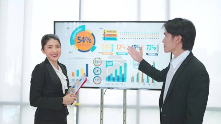 Téléchargez les photos : Deux entrepreneurs asiatiques professionnels présentent la stratégie de données de croissance de l'entreprise sur la télévition pour expliquer lors de la réunion de l'atelier de bureau - en image libre de droit