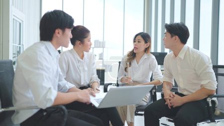 Téléchargez les photos : L'équipe de jeunes gens d'affaires asiatiques se rencontrent et discutent en utilisant un ordinateur portable montrant les données au bureau - en image libre de droit