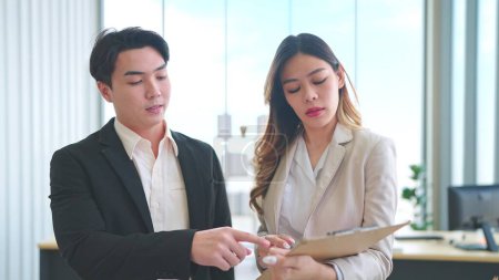 Foto de Dos empresarios asiáticos caminando y hablando de su negocio en la oficina corporativa moderna - Imagen libre de derechos