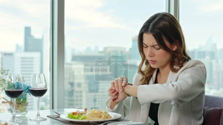 Foto de Hermosa mujer mirando el watchat y molesto porque su novio llega tarde a la cena en un restaurante - Imagen libre de derechos