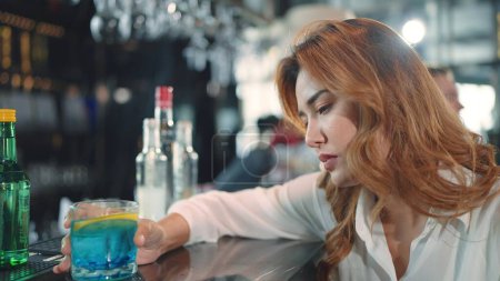 Foto de Una mujer aburrida y triste bebiendo bebida de cóctel sentado en el mostrador del bar en el restaurante - Imagen libre de derechos