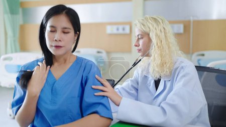 Téléchargez les photos : Femme blanche médecin en uniforme blanc examinant le corps d'une patiente à l'hôpital - en image libre de droit