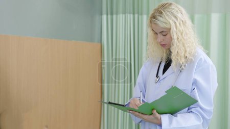 Téléchargez les photos : Profession Femme caucasienne médecin écrivant des informations de traitement sur presse-papiers à l'hôpital - en image libre de droit