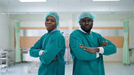 Foto de Dos hombres afroamericanos médico profesional en brazos cruzados posición mirando a la cámara en el hospital - Imagen libre de derechos
