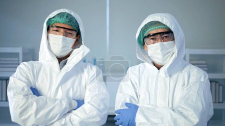 Photo for Portrait of two Asian scientists wearing protection glasses in white coat is looking at camera and smiling while standing in laboratory, Research, biochemistry, pharmaceutical medicine - Royalty Free Image