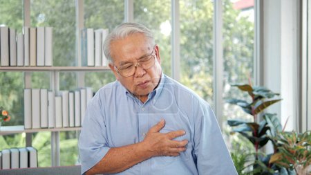 Foto de Anciano hombre asiático con dolor en el pecho que sufre de un ataque al corazón. Un hombre agarrándose del pecho por un dolor agudo. Síntoma de ataque cardíaco-Salud y concepto médico - Imagen libre de derechos
