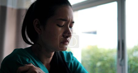 Téléchargez les photos : Jeune femme asiatique déprimée assise sur le lit à l'hôpital. Elle a souligné et anxieux inquiet sa santé - en image libre de droit