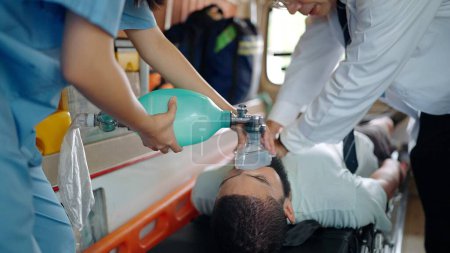 Foto de Paramédico realizando RCP del hombre lesionado en camillas en el coche de emergencia. Asistente médico usando una máscara para respirar - Imagen libre de derechos