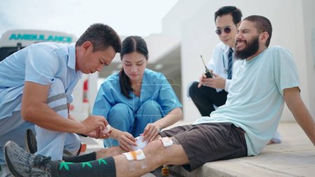 Foto de Médico paramédico de primeros auxilios hombre de lesionado en accidente de rodilla y utilizar comunicaciones por radio para llamar a una ambulancia - Imagen libre de derechos