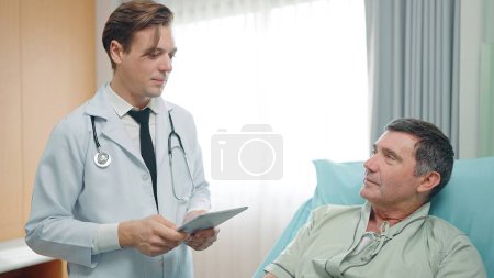 Photo for A young doctor describes the condition of an elderly patient lying on a bed in the hospital - Royalty Free Image