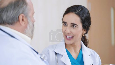 Photo for Close up face of hispanic latino woman doctor in white medical coat talking with senior male doctor supervisor - Royalty Free Image