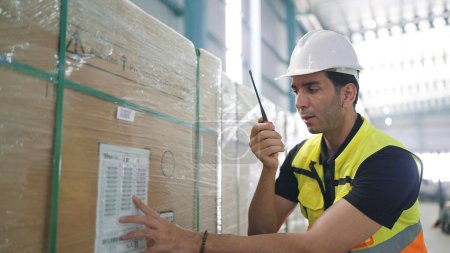 Téléchargez les photos : Professionnel caucasien élégant jeune ingénieur tenant une communication radio parler avec un collègue pour inspecter les produits dans l'usine - en image libre de droit