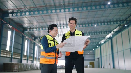 Photo for Two professional engineer male worker talking and discuss to work holding and looking at paper work in factory Industrial - Royalty Free Image