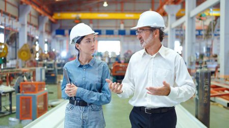 Photo for Two professional engineer man and woman manager leader wearing helmet and walking in factory talking and discussing for work - Royalty Free Image