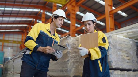 Foto de Dos trabajadores industriales en uniforme hablar y comprobar la calidad y el stock de techo de chapa metálica en la fábrica de fabricación - Imagen libre de derechos