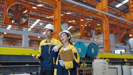 Téléchargez les photos : Deux employés de fabrication dans des chapeaux durs marchent dans l'industrie de l'usine de fabrication de métaux en acier - en image libre de droit