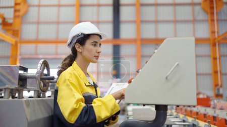 Téléchargez les photos : Jeune femme technicienne dans la machine de contrôle de fabrication de système de contrôle et de réparation uniforme à l'usine industrielle - en image libre de droit