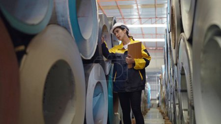 Téléchargez les photos : Hispanique latina femme ouvrière industrielle vérifier la qualité à l'intérieur des tuyaux en acier métal à l'usine de fabrication de l'industrie - en image libre de droit