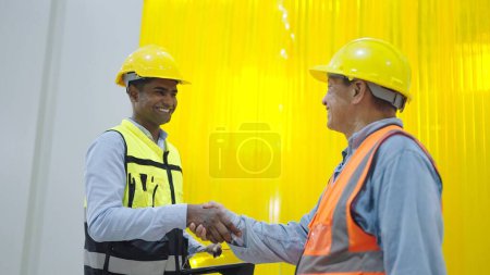Photo for Two professional factory warehouse workers shaking hands together while standing at warehouse - Royalty Free Image