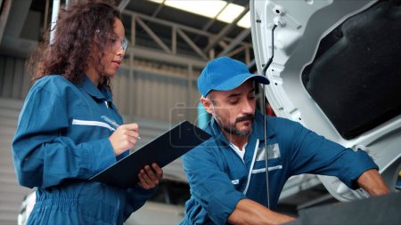Photo for Two Auto mechanic checking car engine oil in car auto repair service center. Car repair and maintenance. Car mechanic working at automotive service center - Royalty Free Image