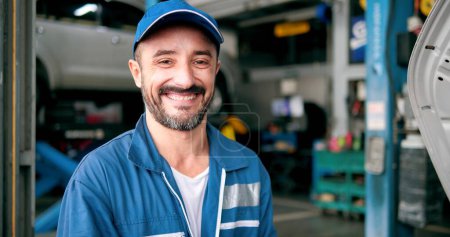 Foto de Cara sonriente del hombre caucásico mecánico de coches de pie mirando a la cámara en el automóvil - Imagen libre de derechos