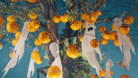 Photo for Halloween pumpkins and white ghost dolls hanging from trees on Halloween night - Royalty Free Image