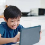 Asian little boy play games on tablet at home on weekends. The children addicted to games concept