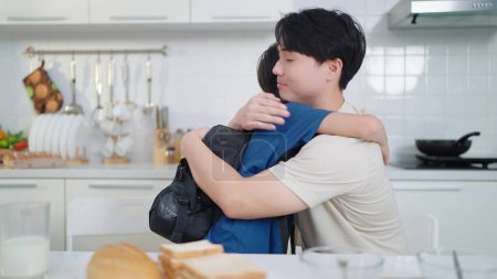 Alleinerziehender asiatischer Vater und Sohn umarmen sich, bevor sie zur Schule gehen. Glückliches Familienkonzept. Konzept Alleinerziehender