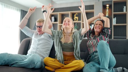 Photo for Cheerful happy Caucasian family cheering for favorite team and it scoring goal and winning game. mother, father and daughter watching TV with sports celebration cheers, hands holding up - Royalty Free Image