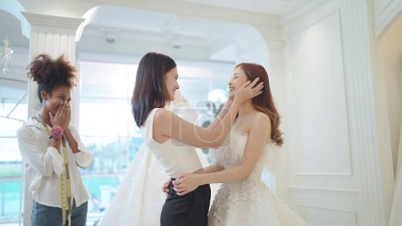 Foto de Asiático hermosas damas de honor felicitar a su amigo en convertirse en una novia elegir el vestido de novia blanco para la ceremonia de boda en el estudio de la boda - Imagen libre de derechos