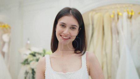 Téléchargez les photos : Visage souriant de belle mariée heureuse en robe blanche regardant la caméra au studio de mariage - en image libre de droit