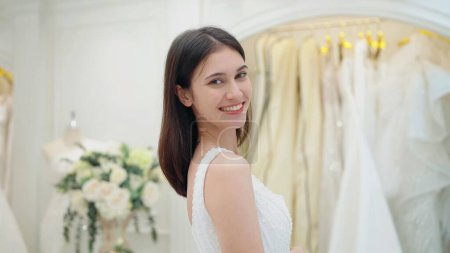 Téléchargez les photos : Visage souriant de belle mariée heureuse en robe blanche regardant la caméra au studio de mariage - en image libre de droit