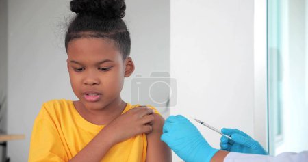 Téléchargez les photos : Des enfants afro-américains se font vacciner à la clinique ou à l'hôpital, avec une infirmière s'injectant le vaccin pour obtenir une immunité pour se protéger. vaccin pour enfants concept - en image libre de droit
