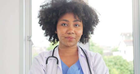 Téléchargez les photos : Médecin noir afro-américain confiant qui sourit à la caméra et aux bras croisés, Médecin noir professionnel en blouse blanche prêt à sauver des vies - en image libre de droit