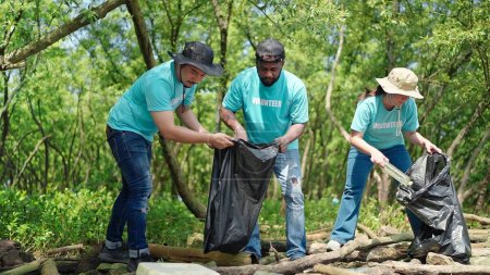 Téléchargez les photos : Un groupe de bénévoles aide à ramasser les déchets en nettoyant les sacs à ordures dans la forêt verte. Activités de RSE. Responsabilité sociale des entreprises. Problème environnemental. Journée de l'environnement - en image libre de droit