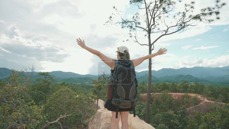 Foto de Mujer viajera llevando una mochila mirando alrededor hermosa de la vista de la montaña y levanta los brazos en el aire, feliz y borracho en la vida y la felicidad - Imagen libre de derechos