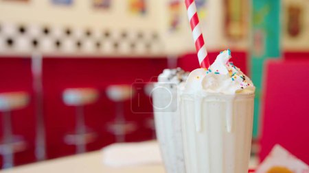 Téléchargez les photos : Gros plan mettant du papier à boire de la paille dans des milkshakes avec de la crème fouettée dans du verre, Délicieuse boisson dessert - en image libre de droit